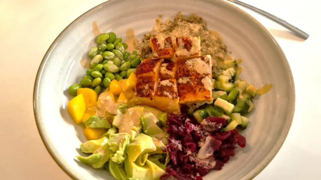 En skål med lax, quinoa, edamamebönor, mango, avokado och rödbetor. Ett perfekt recept nyttig mat för en hälsosam lunch.