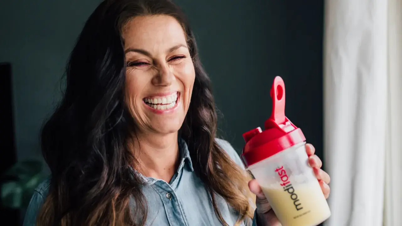 Glad kvinna skrattar med en shaker från Modifast diet.