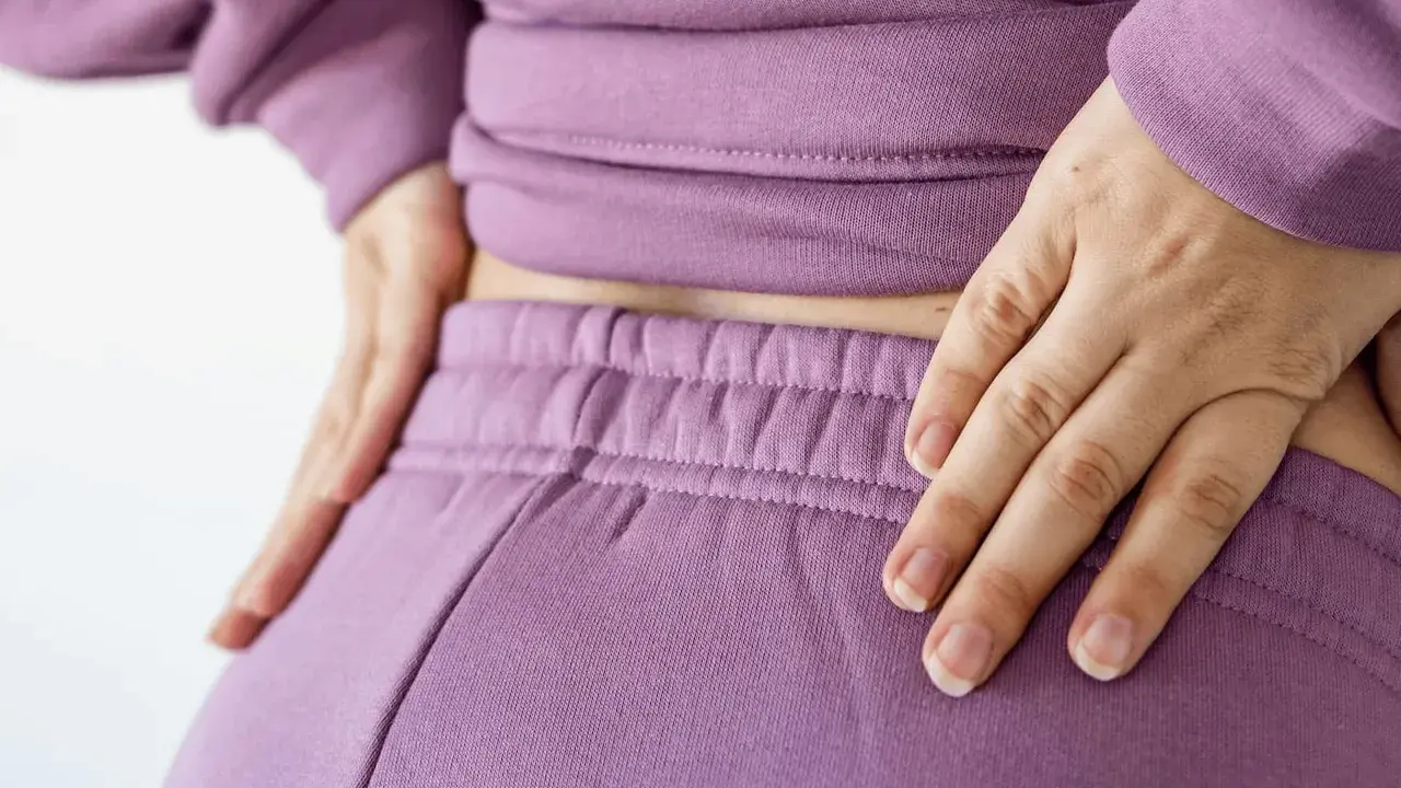 Händer vilar på ryggslut och höfter, en påminnelse om hormonell obalans efter graviditet.