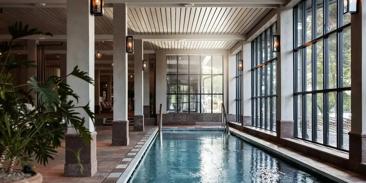 Inre poolområde med stora fönster och grönska utanför, perfekt för ett yoga retreat i Stockholm.