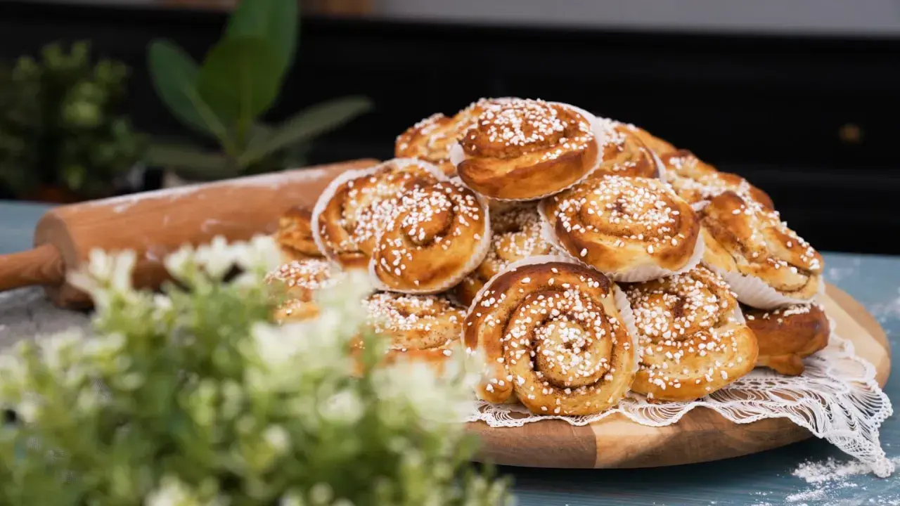 En hög med gyllene, nybakade kanelbullar, strösslade med pärlsocker. Perfekta för fikat, dessa nyttiga bullar ser oemotståndliga ut.