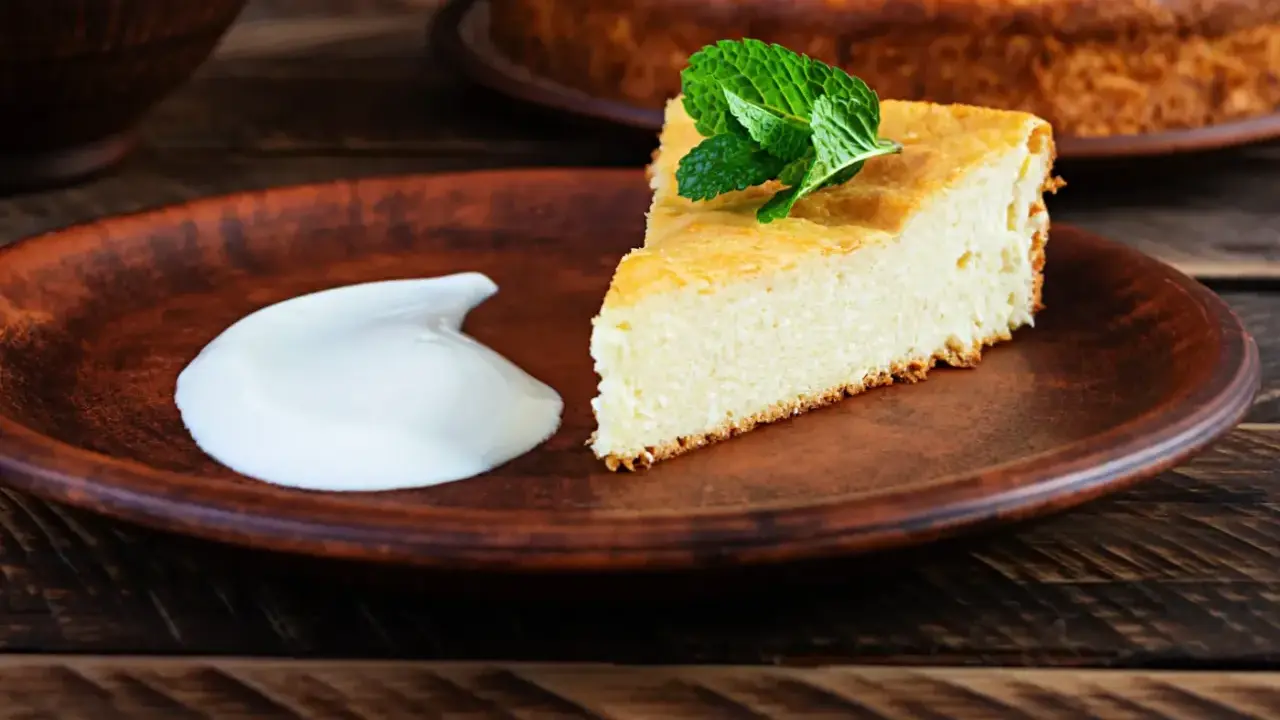 En bit fluffig, nyttig cheesecake med mynta och en klick grädde på en lerbricka.