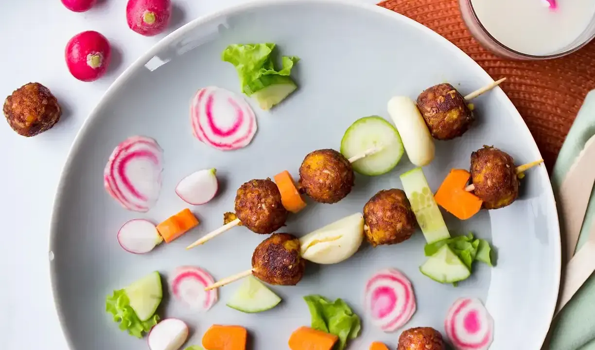 Vegetariska mat för barn på ett fat med köttbullar, gurka, morötter och rädisor. En festlig och hälsosam måltid!
