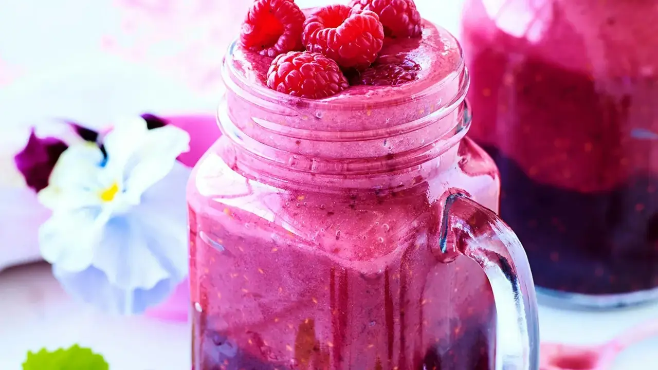 En härlig smoothie i ett glas med färska hallon på toppen. Ett perfekt smoothie recept för en solig dag.