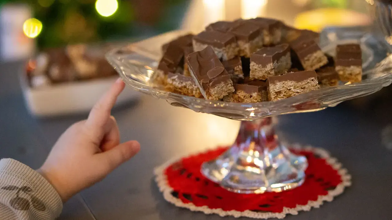 Barnfingret pekar mot en bricka med chokladöverdragna flapjacks. Ett enkelt flapjacks recept som alla kan lyckas med.