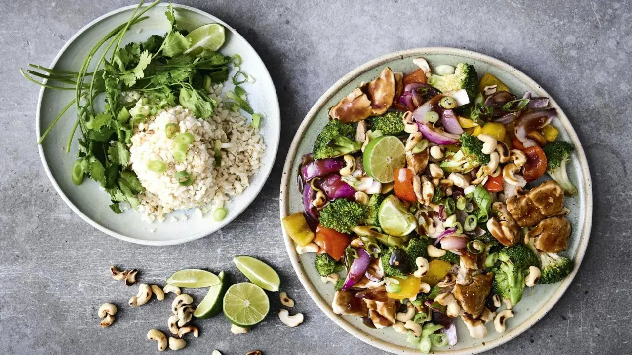 Två tallrikar med nyttig fredagsmat: ris med koriander och grönsaker med kyckling, cashewnötter och lime.