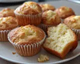 En tallrik med gyllene mellanmålsmuffins barn älskar. En muffin är uppdelad och visar en mjuk insida.