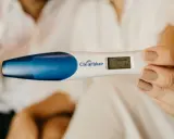 En hand håller ett digitalt graviditetstest som visar "Gravid 3+". En oväntad upptäckt, gravid utan att veta.