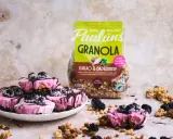Rosa yoghurtglass med bär och granola, perfekt för ett snabbt yoghurtglass recept. Paulúns granola i bakgrunden.