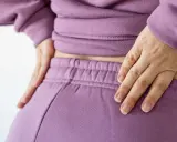 Händer vilar på ryggslut och höfter, en påminnelse om hormonell obalans efter graviditet.