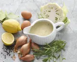 En skål med nyttig bearnaisesås omgiven av ingredienser som citron, ägg, schalottenlök, pepparkorn, dragon och blomkål.