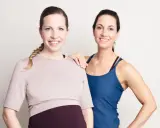 Två glada kvinnor, en gravid, poserar. De är klädda i träningskläder och ser ut att vara redo att lyfta tungt, gravid eller ej.