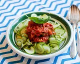En skål med zucchinipasta och en smakrik tomatsås, toppad med basilika. Perfekt för goda nyttiga recept!