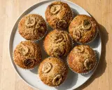 Sju gyllene bananmuffins med skivor av banan på toppen, redo att avnjutas. Ett perfekt bananmuffins recept för fika.