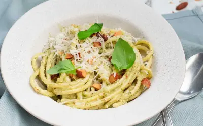 En portion krämig pasta med pesto, toppad med riven ost, nötter och basilika. Perfekt spagetti koktid för en snabb och god måltid.