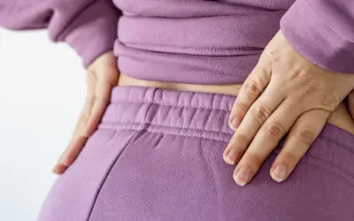 Händer vilar på ryggslut och höfter, en påminnelse om hormonell obalans efter graviditet.