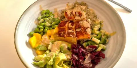 En skål med lax, quinoa, edamamebönor, mango, avokado och rödbetor. Ett perfekt recept nyttig mat för en hälsosam lunch.