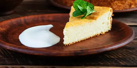 En bit fluffig, nyttig cheesecake med mynta och en klick grädde på en lerbricka.