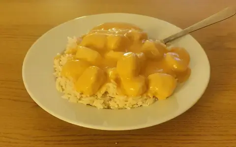 En tallrik med ris och krämiga fiskbullar i en gul sås. En nyttig och god måltid.
