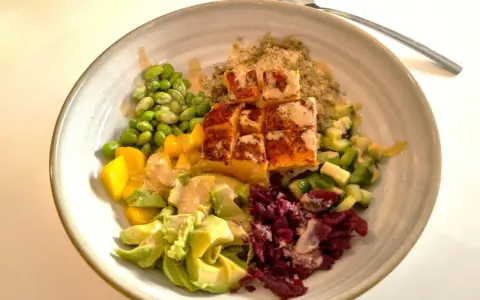 En skål med lax, quinoa, edamamebönor, mango, avokado och rödbetor. Ett perfekt recept nyttig mat för en hälsosam lunch.