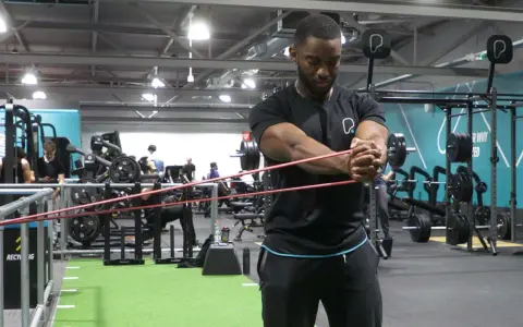 Man utför pallof press med gummiband i ett gym.