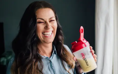 Glad kvinna skrattar med en shaker från Modifast diet.