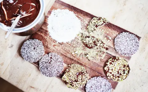 Riskakor med choklad och kokos eller pistage. En skål med smält choklad och en sked står bredvid.