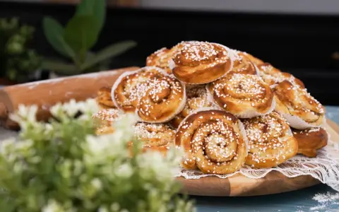 En hög med gyllene, nybakade kanelbullar, strösslade med pärlsocker. Perfekta för fikat, dessa nyttiga bullar ser oemotståndliga ut.