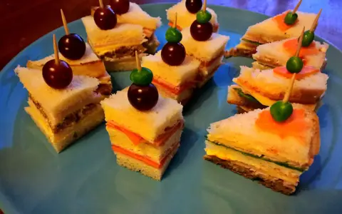 Små, färgglada smörgåsar med vindruvor och gröna oliver, perfekta som roliga snittar barn älskar.