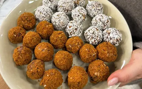 En tallrik med hemgjorda pepparkaksbollar och dadlar, vissa rullade i kokosflingor.