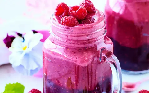 En härlig smoothie i ett glas med färska hallon på toppen. Ett perfekt smoothie recept för en solig dag.