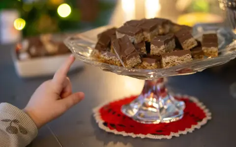 Barnfingret pekar mot en bricka med chokladöverdragna flapjacks. Ett enkelt flapjacks recept som alla kan lyckas med.