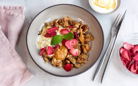 En skål med granola, yoghurt, jordgubbar, jordnötssmör och chiafrön. En perfekt nyttig frukost för en bra start på dagen.
