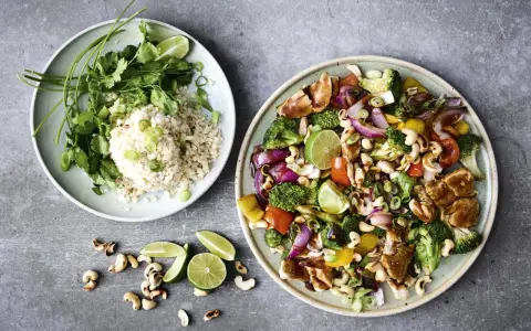 Två tallrikar med nyttig fredagsmat: ris med koriander och grönsaker med kyckling, cashewnötter och lime.