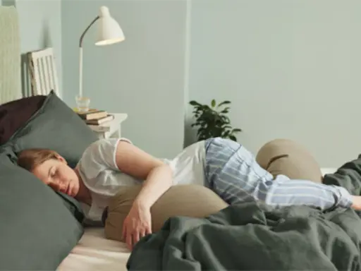 En kvinna sover i sängen, omgiven av kuddar. Hon undrar hur vet man om slemproppen gått.