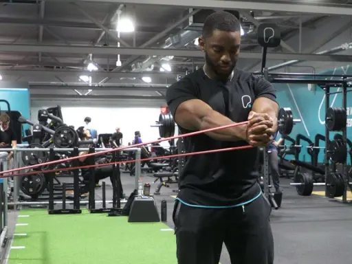 Man utför pallof press med gummiband i ett gym.