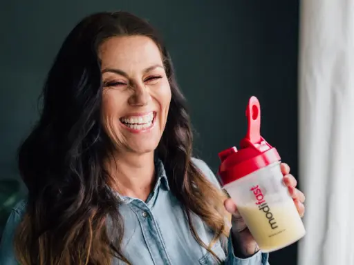 Glad kvinna skrattar med en shaker från Modifast diet.