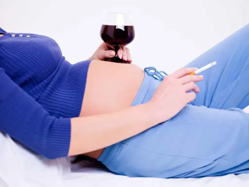 Gravid kvinna med ett glas rött vin och en cigarett. Matlagningsvin gravid är inte rekommenderat.