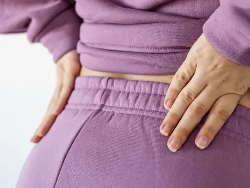 Händer vilar på ryggslut och höfter, en påminnelse om hormonell obalans efter graviditet.