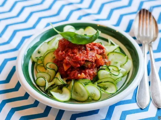 En skål med zucchinipasta och en smakrik tomatsås, toppad med basilika. Perfekt för goda nyttiga recept!