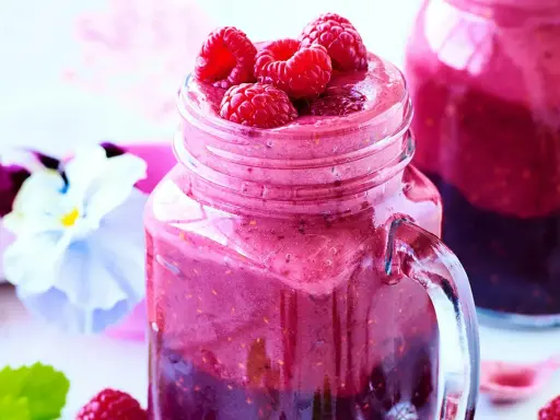 En härlig smoothie i ett glas med färska hallon på toppen. Ett perfekt smoothie recept för en solig dag.