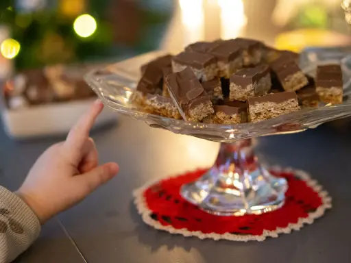 Barnfingret pekar mot en bricka med chokladöverdragna flapjacks. Ett enkelt flapjacks recept som alla kan lyckas med.