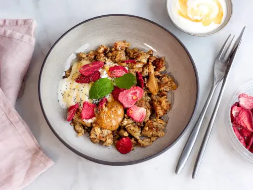 En skål med granola, yoghurt, jordgubbar, jordnötssmör och chiafrön. En perfekt nyttig frukost för en bra start på dagen.