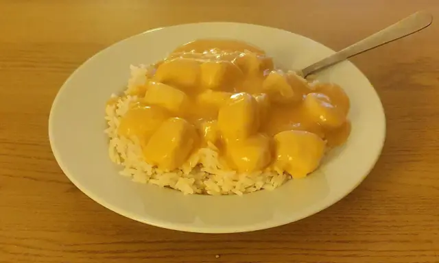 En tallrik med ris och krämiga fiskbullar i en gul sås. En nyttig och god måltid.