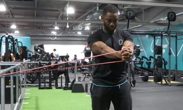 Man utför pallof press med gummiband i ett gym.