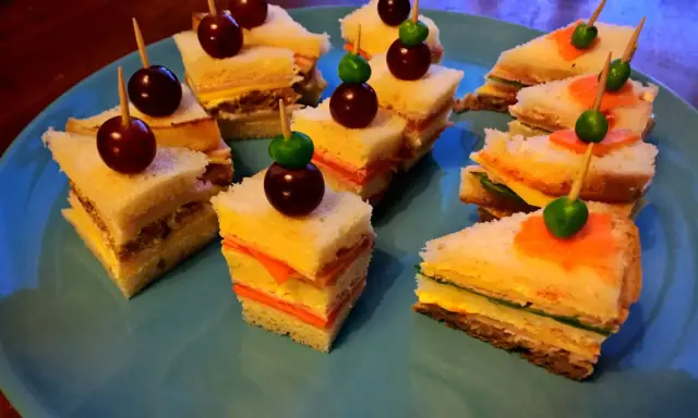 Små, färgglada smörgåsar med vindruvor och gröna oliver, perfekta som roliga snittar barn älskar.