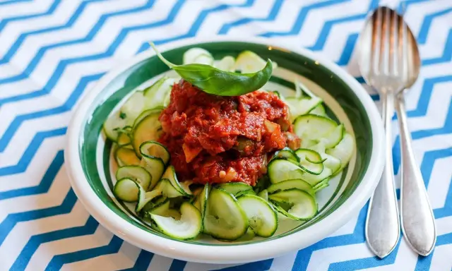 En skål med zucchinipasta och en smakrik tomatsås, toppad med basilika. Perfekt för goda nyttiga recept!
