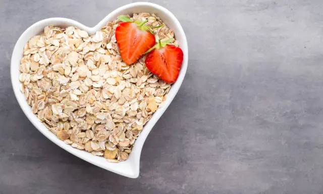 Hjärtformad skål fylld med havregryn och jordgubbar. Ett hälsosamt val för frukost, fiberhavregryn vs havregryn.