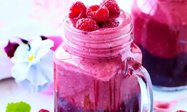 En härlig smoothie i ett glas med färska hallon på toppen. Ett perfekt smoothie recept för en solig dag.