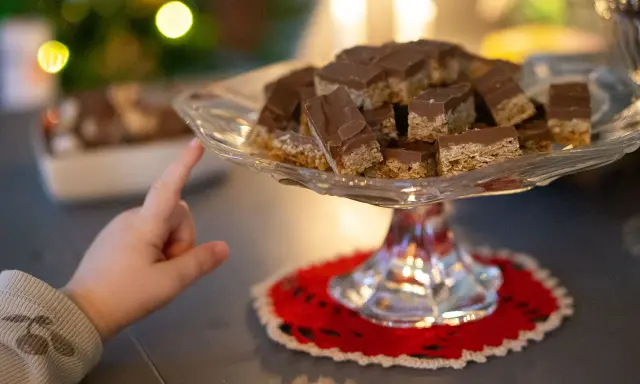 Barnfingret pekar mot en bricka med chokladöverdragna flapjacks. Ett enkelt flapjacks recept som alla kan lyckas med.